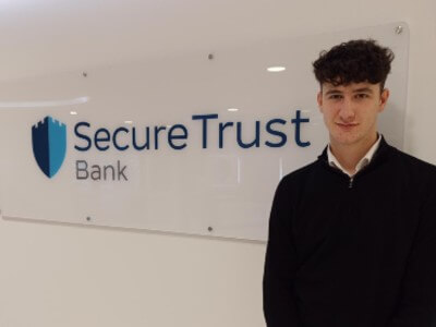 Harry standing next to Secure Trust Bank signage